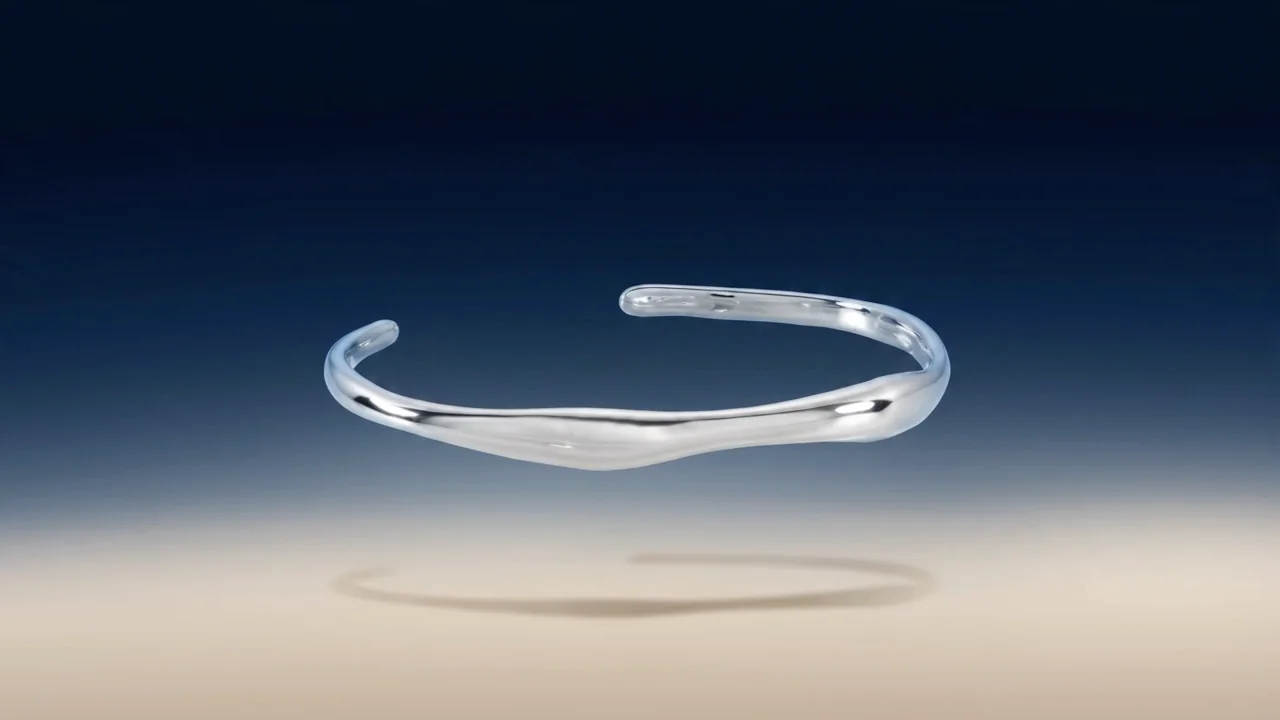 A sculpted silver cuff floating above its shadow
